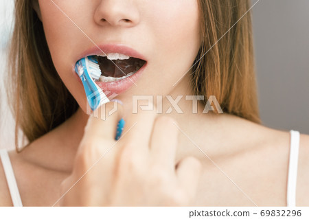 A young woman is brushing teeth in the bathroom. Reflection in the mirror A young woman is brushing teeth in the bathroom. Reflection in the mirror 69832296