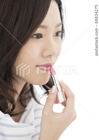 A woman applying lipstick A woman applying lipstick 69834275