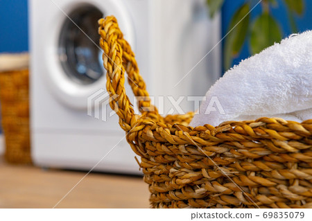 Washing machine with laundry on blue wall background Washing machine with laundry on blue wall background 69835079