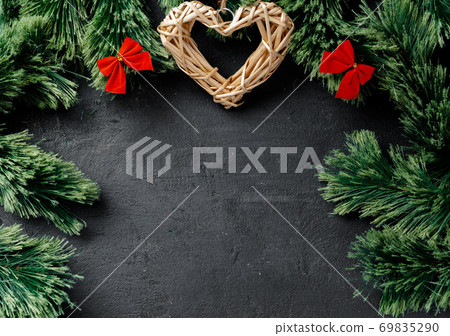 Fir tree branches with wooden heart on black Fir tree branches with wooden heart on black 69835290