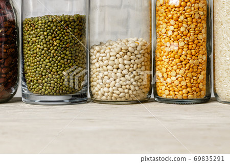 Raw cereals or beans in glass jars close up. Vegan and vegetarian food. Raw cereals or beans in glass jars close up. Vegan and vegetarian food. 69835291
