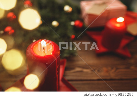 Burning Christmas red candle on brown wooden table Burning Christmas red candle on brown wooden table 69835295