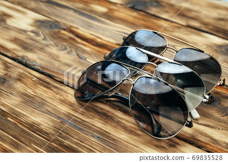 Set of dark sunglasses on brown wooden surface 69835528