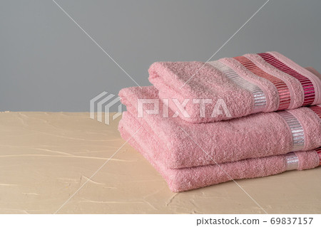 Pile of clean new towels against grey wall 69837157