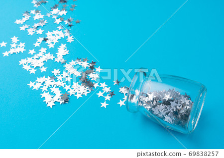 Glass jar with scattered confetti on blue background 69838257