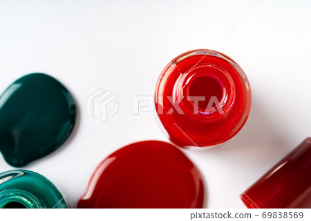 Nail polishes spilled out of bottles on white background Nail polishes spilled out of bottles on white background 69838569