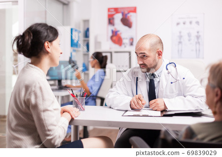 Doctor talking with daughter of senior patient 69839029