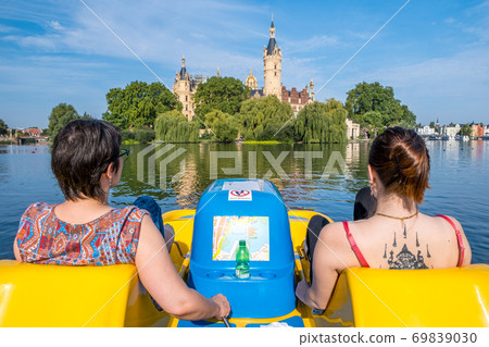 Girls on a catamaran look at the beautiful fairytale Schwerin castle. 69839030