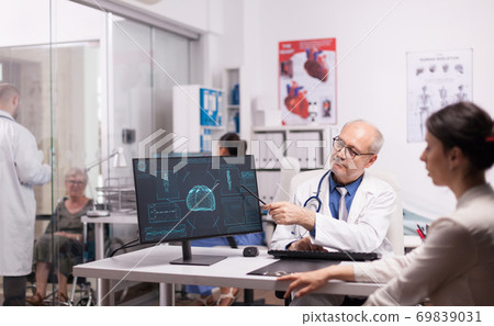 Doctor with grey hair pointing at x-ray 69839031