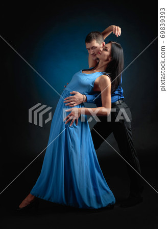 Young beautiful woman in long blue dress and man in blue shirt dancing tango. 69839393