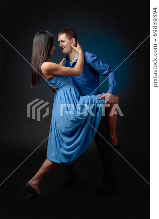 Young beautiful woman in long blue dress and man in blue shirt dancing tango. 69839394