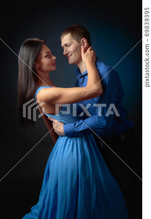 Beautiful woman in long blue dress and man in blue shirt dancing tango. 69839395