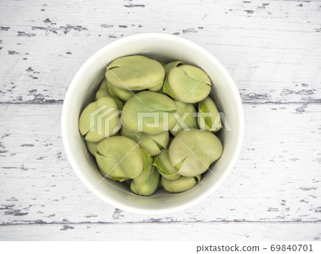 Boiled broad beans in a white pot on a white wooden table 69840701