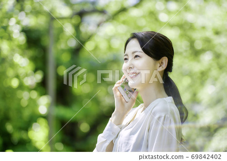 使用智能手機的少婦在新鮮的綠色 使用智能手機的少婦在新鮮的綠色 69842402