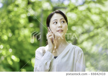 Young woman using a smartphone in the fresh green Young woman using a smartphone in the fresh green 69842410