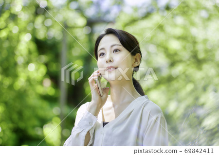 Young woman using a smartphone in the fresh green Young woman using a smartphone in the fresh green 69842411