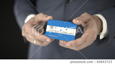 Businessman holds credit card with printed flag of Honduras in his hands, fictional numbers 69843725