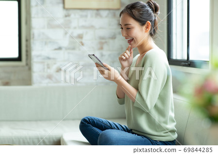 A woman looking at a smartphone with a smile A woman looking at a smartphone with a smile 69844285