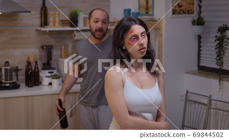 Alcoholic man screaming at beaten woman 69844502