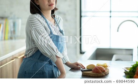 Young housewife stands in the kitchen Young housewife stands in the kitchen 69844590
