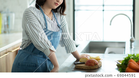 Young housewife stands in the kitchen Young housewife stands in the kitchen 69844591