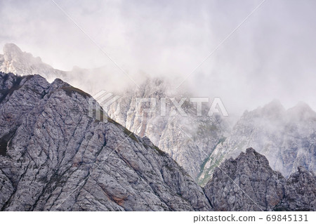 sharp rocky mountain peaks lurk in the clouds sharp rocky mountain peaks lurk in the clouds 69845131