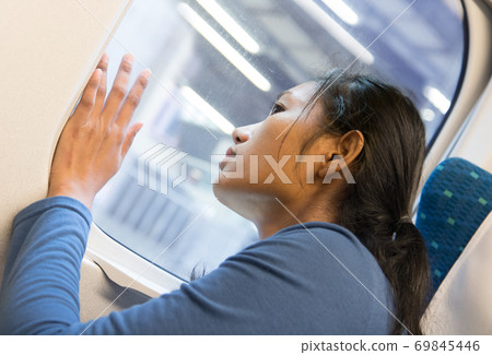 A woman looks out the window of the train on the railway station. A woman looks out the window of the train on the railway station. 69845446
