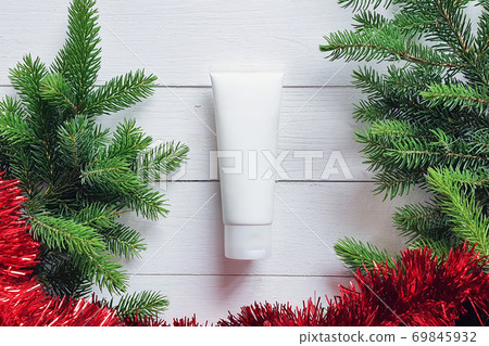 Mockup of white squeeze bottle plastic tube, fir branches and Christmas red garland. Natural organic spa cosmetics concept. Christmas gift flatlay. Mockup of white squeeze bottle plastic tube, fir branches and Christmas red garland. Natural organic spa cosmetics concept. Christmas gift flatlay. 69845932