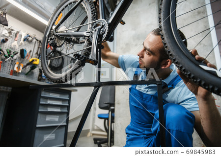 Bicycle repair, man checks the wheel for backlash Bicycle repair, man checks the wheel for backlash 69845983