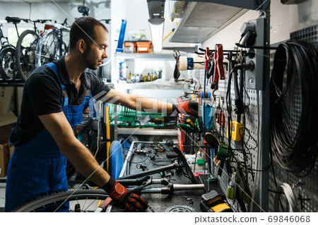 Bicycle repair in workshop, man takes tools 69846068