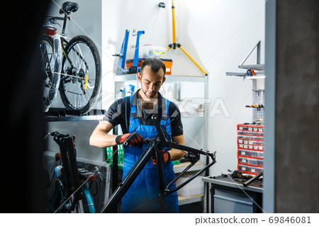 Bicycle repair in workshop, man fixing crank 69846081