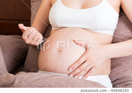 Pregnant woman with insulin syringe in home on bed. Pregnant diabetes concept 69846293