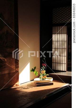 A hanging scroll displayed between the floors of the old house and a gorgeous flower arrangement shining in the sun 69848833