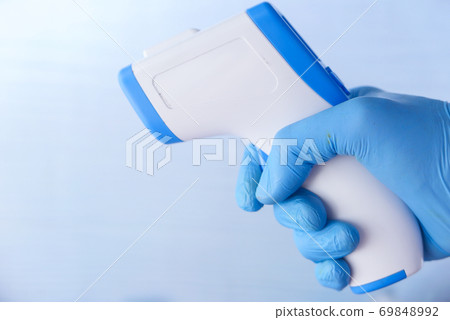 Hand holding infrared thermometer to measuring temperature. Hand holding infrared thermometer to measuring temperature. 69848992