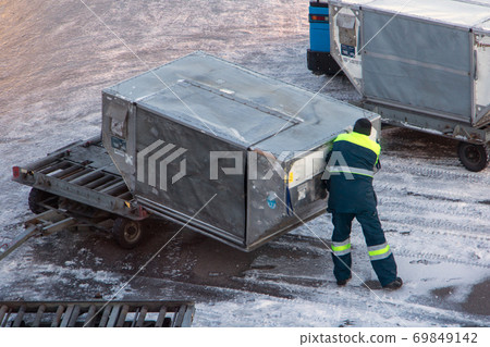 A ground staff of the airport manipulate the freight container. A ground staff of the airport manipulate the freight container. 69849142