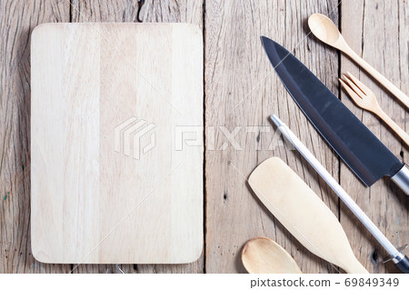Knife and Sharpener with kitchenware on old wooden table background. 69849349