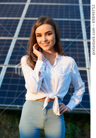 Portrait of a young woman by a solar panel Portrait of a young woman by a solar panel 69849752