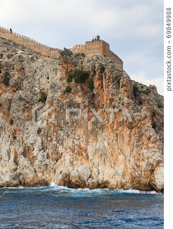 Alanya Castle.  The fortified walls of Alanya Castle in Southern Turkey as viewed from the Mediterranean Sea. The castle is located on a rocky peninsula and dates back to the 13th century. 69849988