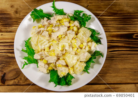 Festive salad with chicken breast, sweet corn, canned pineapple and mayonnaise on wooden table 69850401
