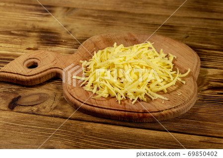 Grated cheese on cutting board on wooden table 69850402