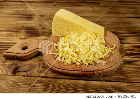 Grated cheese on cutting board on wooden table 69850403