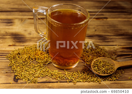 Egyptian yellow tea or Methi Dana drink and fenugreek seeds on wooden table Egyptian yellow tea or Methi Dana drink and fenugreek seeds on wooden table 69850410