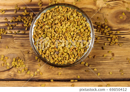 Fenugreek seeds in glass bowl on wooden table Fenugreek seeds in glass bowl on wooden table 69850412