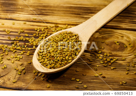 Fenugreek seeds in wooden spoon on wooden table Fenugreek seeds in wooden spoon on wooden table 69850413