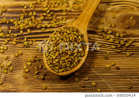 Fenugreek seeds in wooden spoon on wooden table Fenugreek seeds in wooden spoon on wooden table 69850414