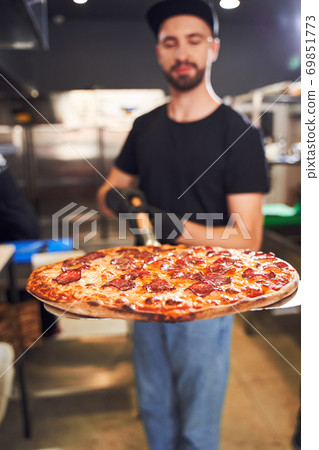 Pizzaiolo holding pizza on peel Pizzaiolo holding pizza on peel 69851773