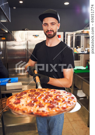 Pizzaiolo holding pizza on peel Pizzaiolo holding pizza on peel 69851774