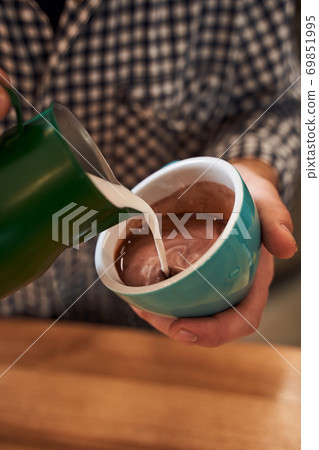 Man's hands pouring a milk into cacao 69851995