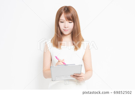 Young woman writing notes on the clipboard Young woman writing notes on the clipboard 69852502