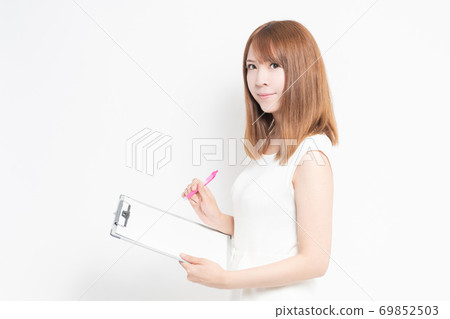 Young woman writing notes on the clipboard 69852503